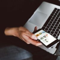 person holding smartphone and laptop