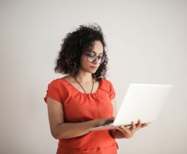 How Blockchain & Cryptography Ensure a Safe Online Gambling Experience Photo of a Woman in an Orange Top Using a Laptop While Standing