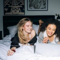 Two Young Women Having Fun While Looking at a Laptop