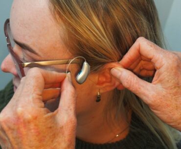 How to Get Into the Hearing Care Business a woman is putting on a pair of glasses