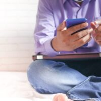 man in white dress shirt and blue denim jeans sitting on bed