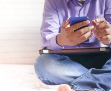 man in white dress shirt and blue denim jeans sitting on bed