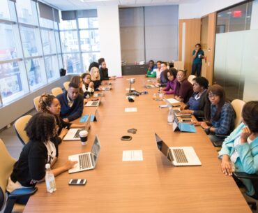 people sitting beside rectangular brown table with laptops