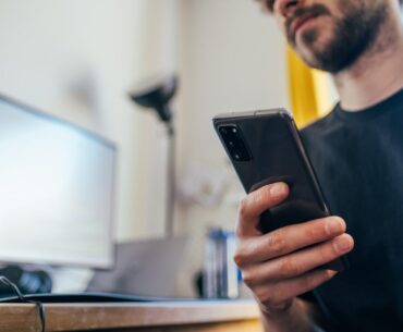 man in black crew neck shirt holding black iphone 5