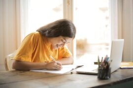 What Is the Optimal Number of Paragraphs in an Essay? Woman in Yellow Shirt Writing on White Paper