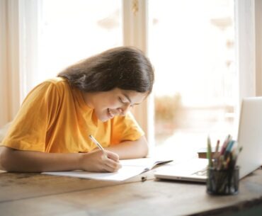 What Is the Optimal Number of Paragraphs in an Essay? Woman in Yellow Shirt Writing on White Paper