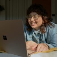 a woman in glasses is looking at a laptop