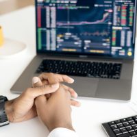 Close-up of a person analyzing stock data on a laptop with graphs and charts visible.