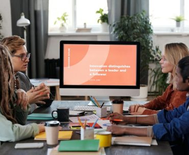 Crafting an Effective Employee Onboarding Process for Long-Term Success A multicultural team collaborating in an office, discussing a project with a visible monitor.