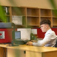 a man sitting at a desk in front of a computer monitor