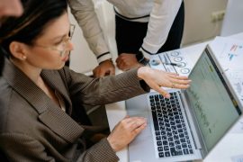 Low Overhead, High Potential: Why Insurance Agencies Make Sense Two professionals focused on analyzing data charts on a laptop in an office setting.