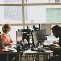 woman in pink shirt sitting in front of black laptop computer