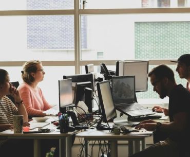 woman in pink shirt sitting in front of black laptop computer