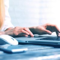 a woman is typing on a laptop computer
