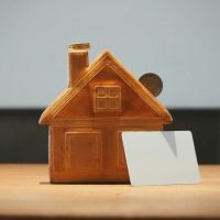 A small house bank with a coin and blank card